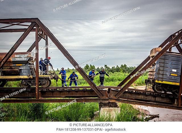 07 December 2018, Argentina, Pichanal: Workers are preparing to salvage a wagon of a freight train belonging to the Argentinian state company Belgrano Cargas