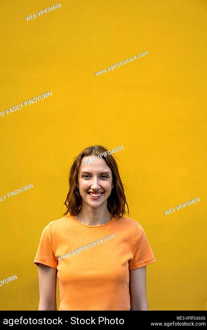 Smiling woman standing in front of yellow wall