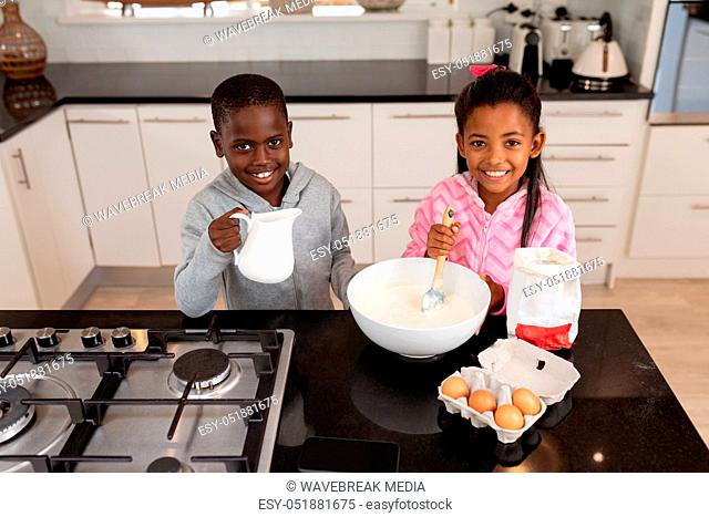 Siblings preparing food on a worktop in kitchen at home