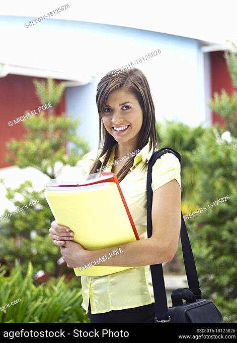 Female student with books looking at camera smiling