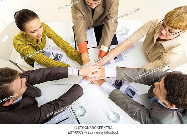 View from above of business partners making pile of hands while sitting at table