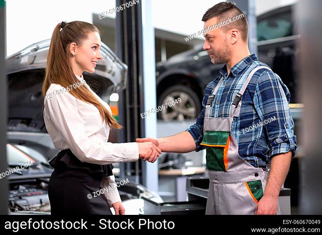 Customer woman having handshake with mechanic man at repair shop. Businesswoman is satisfied with her automobile