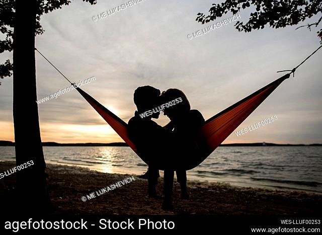 Couple relaxing in hammock during sunset