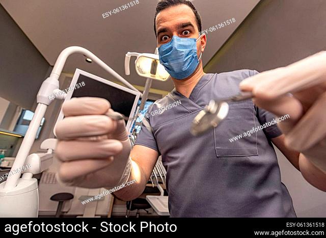 Portrait of male dentist with tools at modern dental office