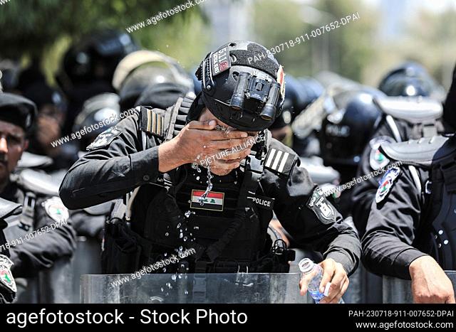 18 July 2023, Iraq, Baghdad: A police officers cools off the intensively hot weather, during a protest near the Turkish Embassy in Baghdad