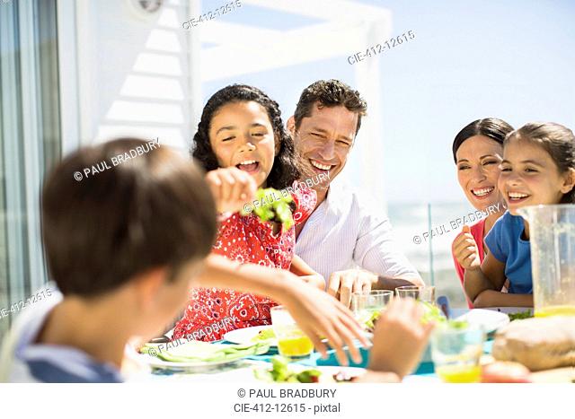 Family eating lunch at table on sunny patio