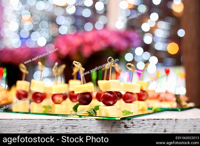 Appetizer of grape, pineapple cubes and cheese are on wooden skewers