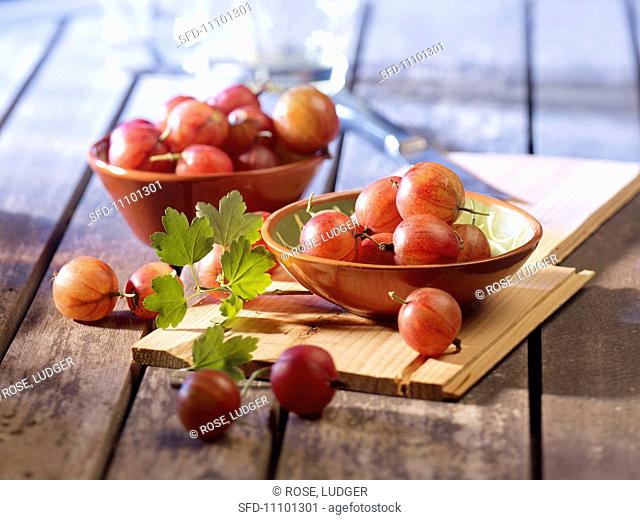 Red gooseberries in bowls and in front of them