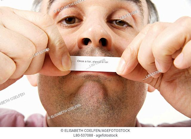 Man holding a piece of paper with a saying in front of his mouth