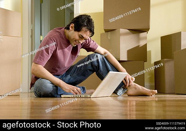 Hispanic man typing on laptop in new house