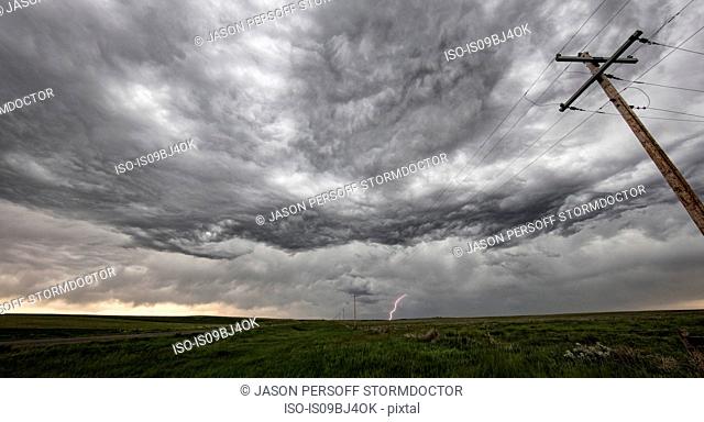 Wave-like asperatus undulatus clouds show gravity waves, a cloud-to-ground lightning strike in the distance, Hillsdale, Wyoming, US