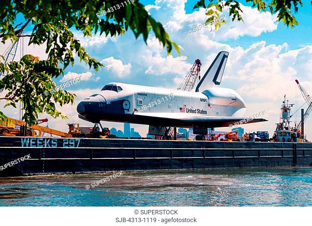 The Space Shuttle prototype Enterprise departs Bayonne after an overnight stop, as it sails by barge from JFK airport to the Intrepid Sea