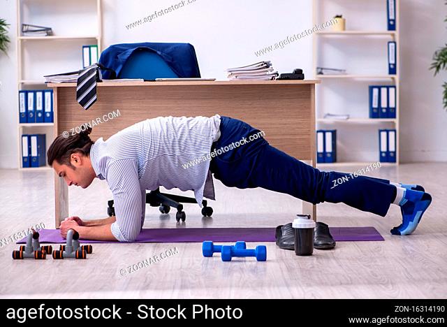 Handsome male employee doing exercises in the office