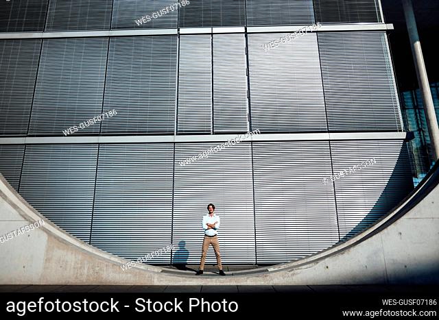 Businessman standing with arms crossed in front of modern building