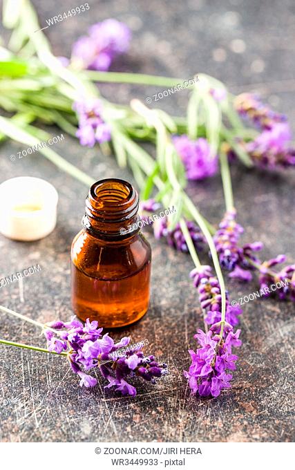 Essential oil and lavender flowers on old table