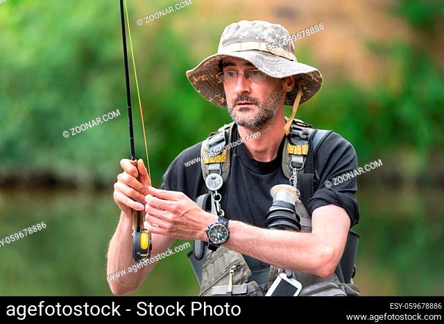 Portrait of mid adult fisherman on river, relaxing and fishing trouts