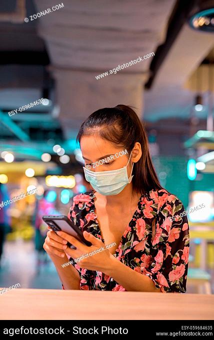 Portrait of beautiful Asian woman wearing face mask for protection against coronavirus Covid-19 vertical shot