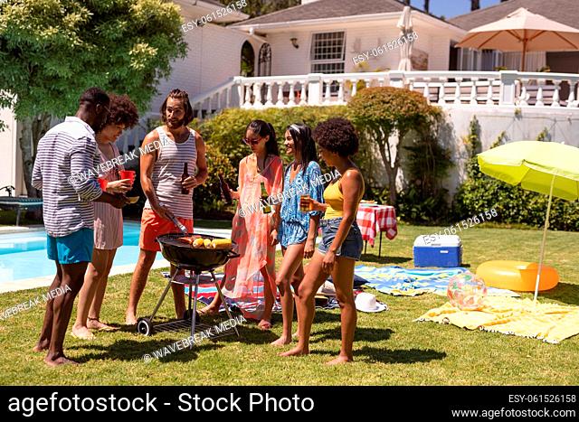 Diverse group of friends having barbecue and talking at a pool party