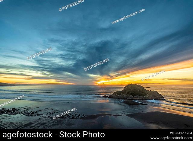 New Zealand, Tongaporutu, Cloudy sky over sandy coastal beach at sunset with¶ÿMotuotamatea¶ÿisland in background