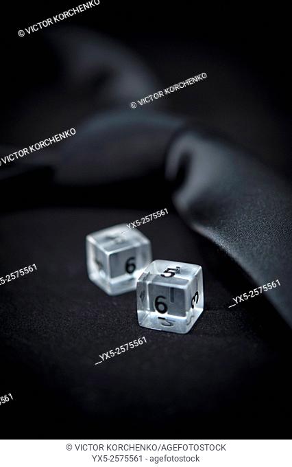 plastic dice on a dark background and a tie