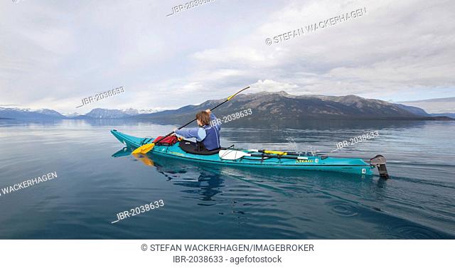 Woman in a sea kayak, paddling, sea kayaking, mountains behind, Tagish Highland, Atlin Lake, British Columbia, Canada, America