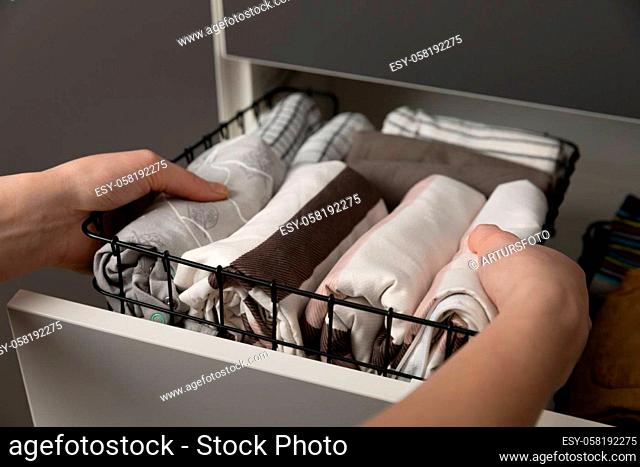 Vertical storage of clothing.Women organize clothes in a modern bedroom. Women sorting clothes in baskets room cleaning concept