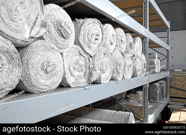 White non-woven fabric in rolls is on the shelves of the warehouse. Covering material. Textiles for the production of rags. Close-up with copy space