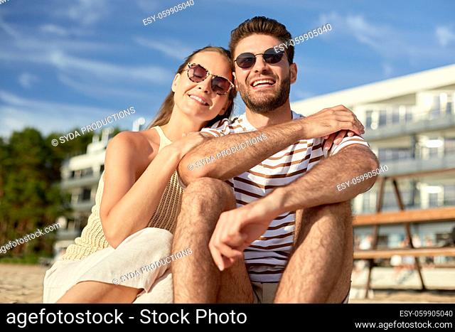 happy couple sitting on summer beach
