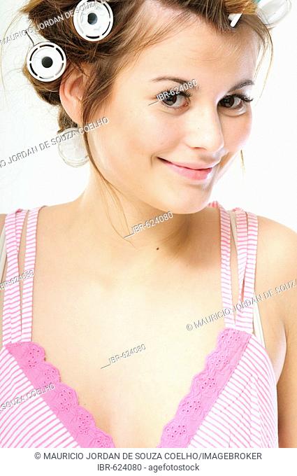 Pretty young brunette woman with curlers in her hair