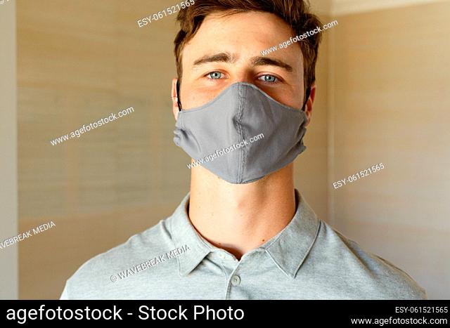 Portrait of caucasian man wearing grey face mask looking straight to camera