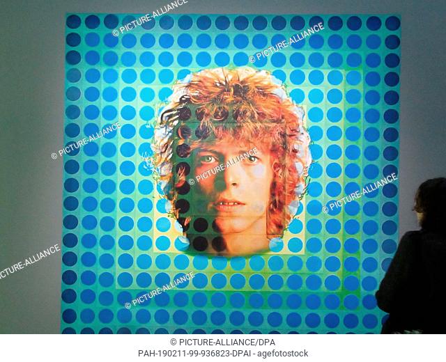 06 February 2019, France (France), Paris: A visitor of the Centre Pompidou stands in front of the record cover picture of ""Space Oddity"" by David Bowie