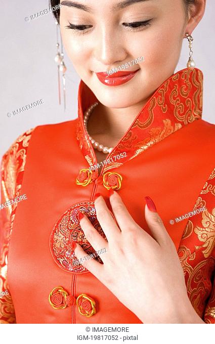 Young woman in cheongsam, hand on chest