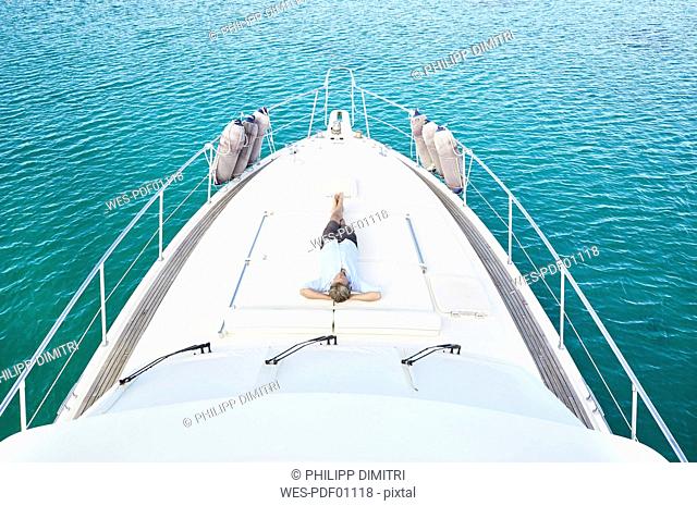 Mature man lying on deck of his motor yacht