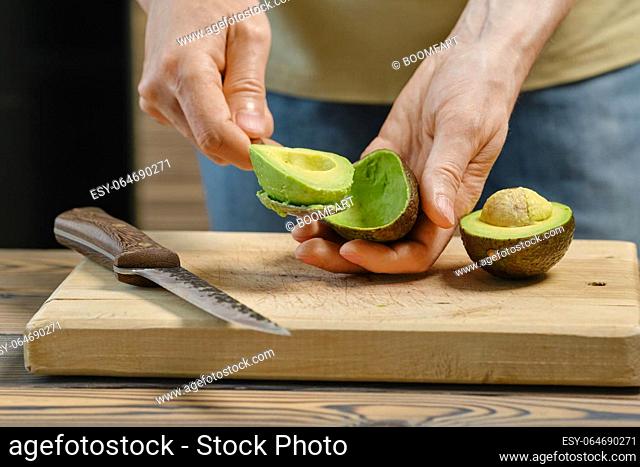 Closeup view of male hand removing avocado from skin with spoon