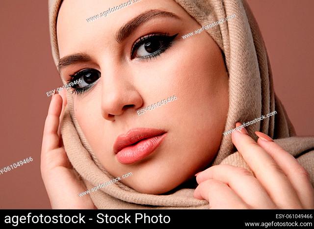 Close-up of young arab muslim woman wearing beige hijab. Isolated. High quality photo
