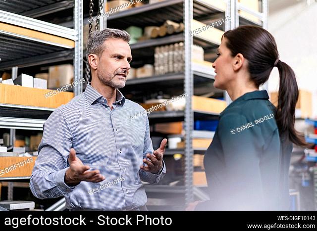 Businessman and businesswoman having a work meeting in storehouse of a factory