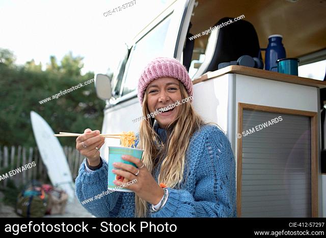 Retrato joven feliz comiendo fideos instantáneos en autocaravana