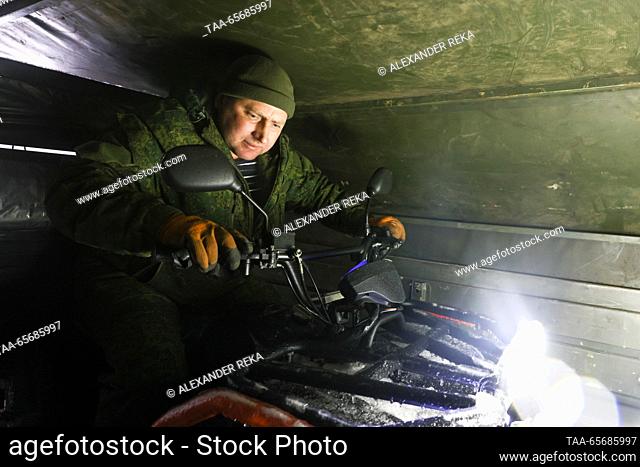 RUSSIA, LUGANSK - DECEMBER 12, 2023: A SEPAR ZOV volunteer loads a quad bike into the back of a truck, more than 20 pieces of special equipment and other...