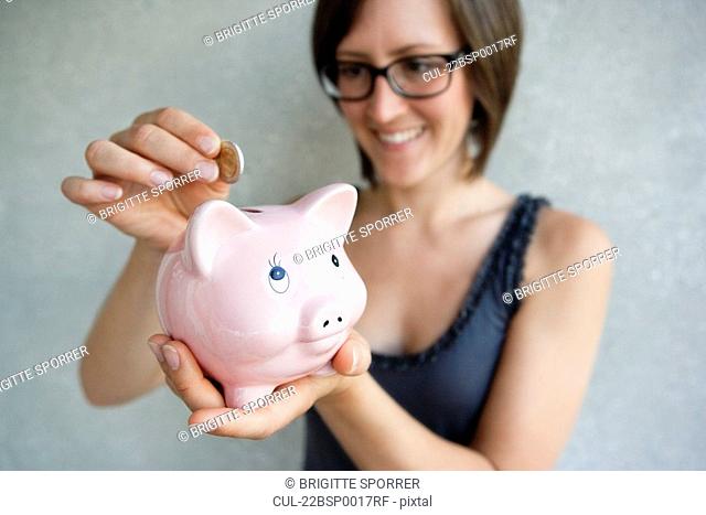 Woman putting coin into piggybank