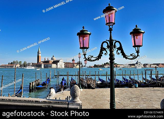 Beautiful wrought iron lamppost photographed from the Palazzo Ducale (Venice, Veneto, Italy) with the landing of gondolas and San Giorgio island in the...