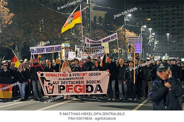 People march with a banner reading 'nonviolent and united against religious wars on German soil! Pegida' during a protest of right-wing initiative PEGIDA...