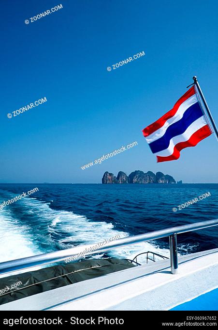Thai flag on the boat over beautiful sea and summer blue sky background. Thailand flag on ferry heading to Phi Phi islands