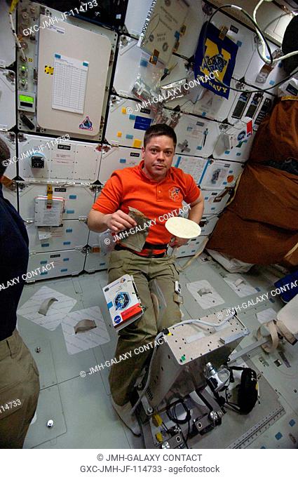 NASA astronaut Robert Behnken, STS-130 mission specialist, is pictured near a tortilla floating freely on the middeck of space shuttle Endeavour while docked...