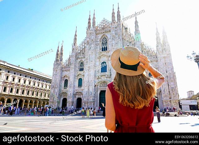 Holidays in Italy. Rear view of traveler girl holds hat in Milan Cathedral Square, Italy