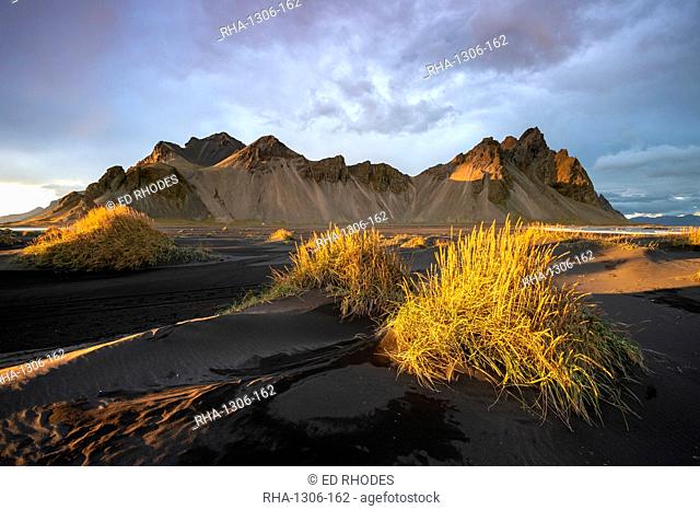 The view of the mountains of Vestrahorn from black volcanic sand beach with grasses at sunset, Stokksnes, South Iceland, Iceland, Polar Regions