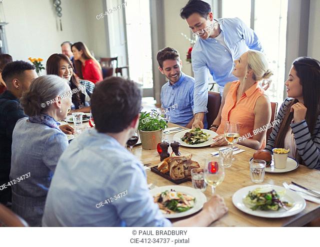 Waiter serving food to friends dining at restaurant table