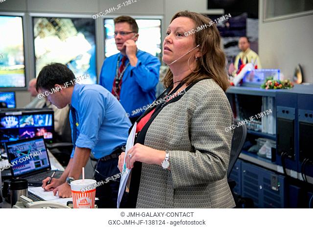 Flight director Dina Contella looks up at a live television downlink from space at her console in the Mission Control Center's space station flight control room...
