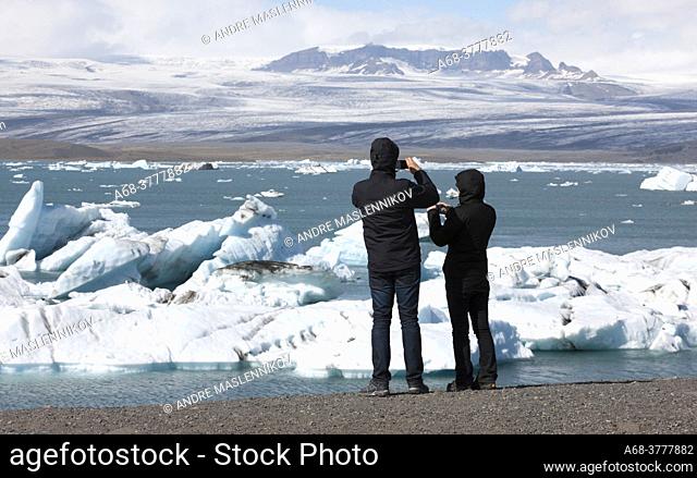 Visitors at Jökulsárlón on Breidamerkursandi. Thousands of people come here every day to see how the glacier tongue calves large icebergs