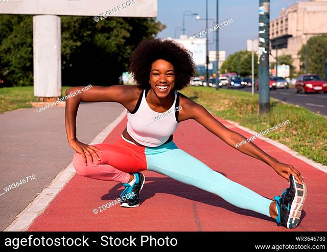 portrait of a young beautiful African American girl doing stretching beautiful summer morning on the streets of the city