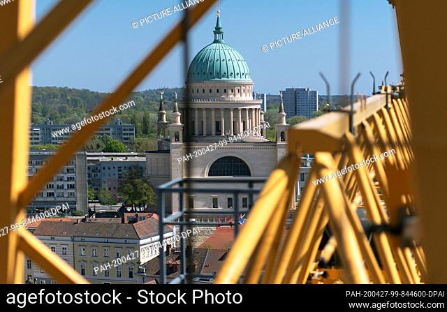 23 April 2020, Brandenburg, Potsdam: The Nikolai Church as well as residential and commercial buildings in the city centre can be seen between the yellow struts...